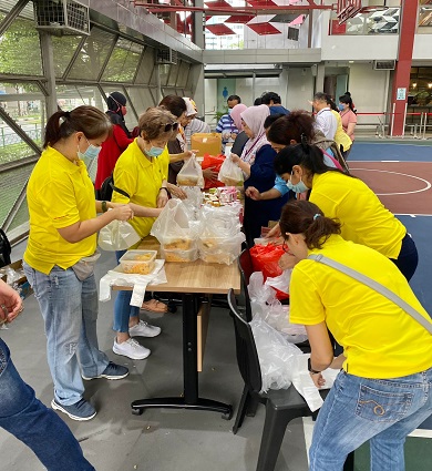 A group of people standing around a table and preparing food for distribution.