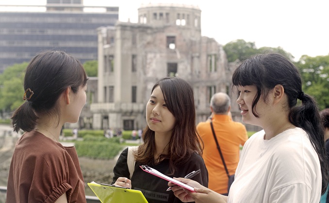 三位女生在交談，背景是原爆圓頂館