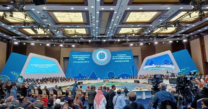 People sitting at and standing around a circular table in front of big blue screens showing the event title