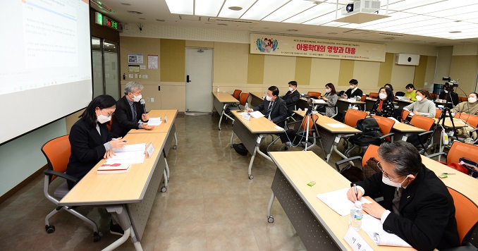 People seated in a hall listening to a speech and taking notes