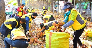 人們穿著黃色的外套在街道上清掃地上的落葉。