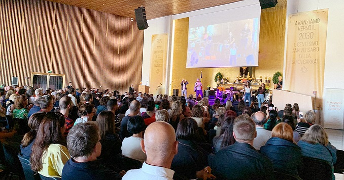 Some 1000 people seated in a big hall watching a musical performance.