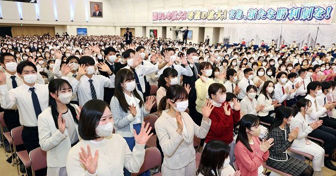 Personas en una gran sala de conferencias aplaudiendo y agitando las manos