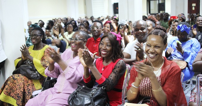 People seated in an event room applauding.