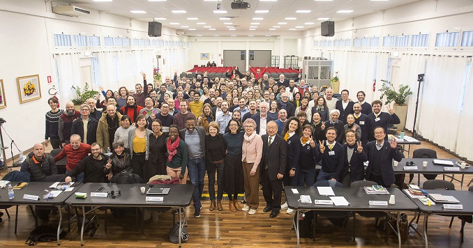 Un grupo numeroso de personas posa para una foto conmemorativa en una sala de conferencias.