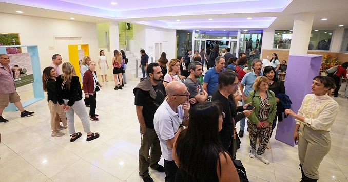 People listening to a presentation, and others exploring an exhibition.