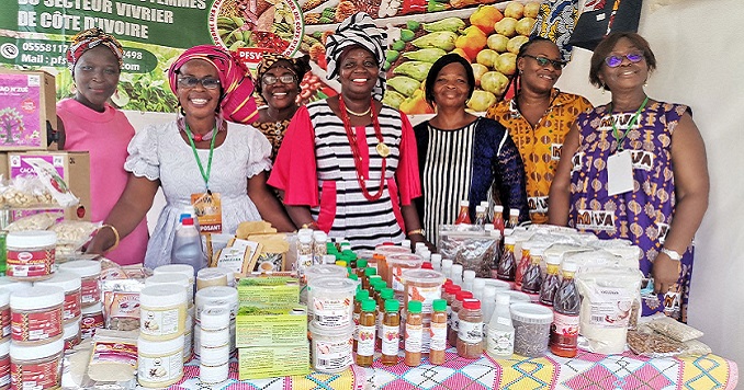 A group of seven smiling women behind a display of food products.