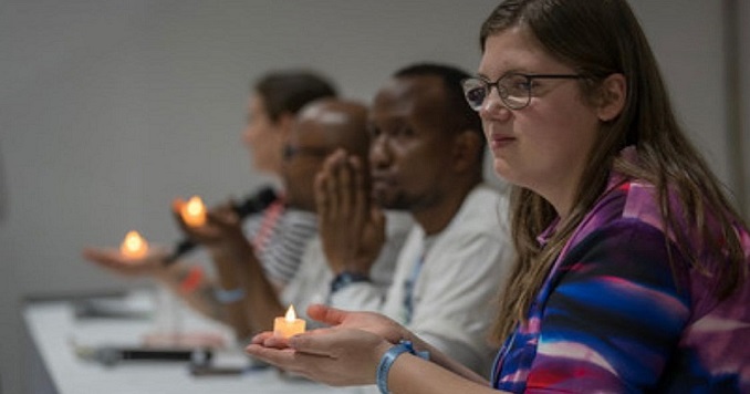 People sitting at a table holding lit candles