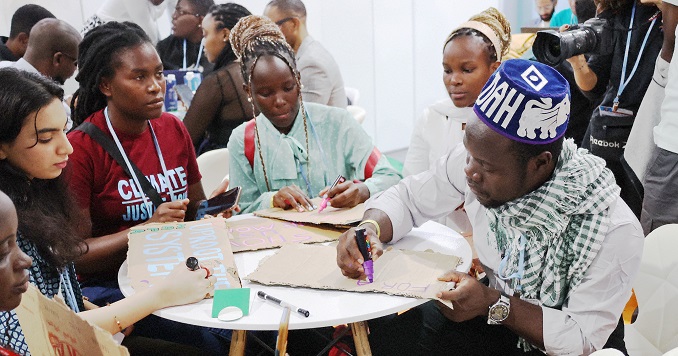 Youth sitting around a table creating signs