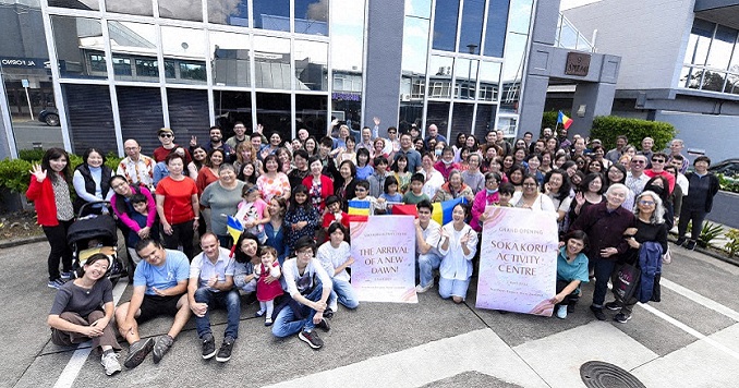 Un numeroso grupo de personas posa para una foto en el exterior de un edificio de varios pisos