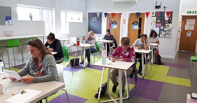 People writing at desks in a classroom.