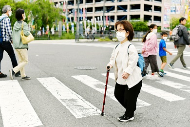 Una persona de corta estatura con un bastón en un cruce peatonal