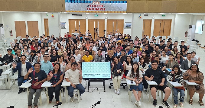 Jóvenes sentados en la sala de conferencia mirando de frente a la cámara y posando para una foto grupal. 