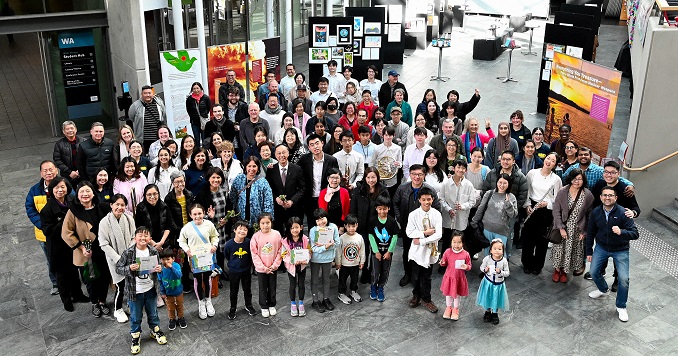 Visitantes de una exposición posan para una foto conmemorativa frente a los paneles de la muestra.