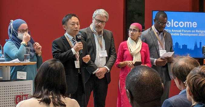 Participants of an interfaith and sustainability event listening to man giving a speech.