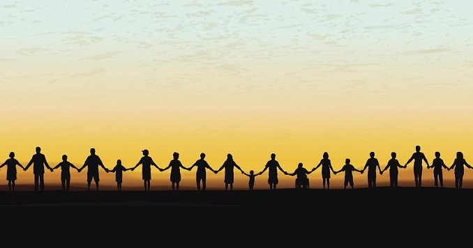 Children and adults holding hands facing a sunset