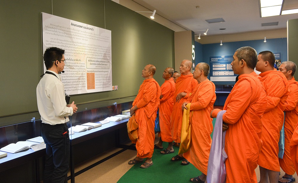 Monks in orange robes viewing the Lotus Sutra exhibition