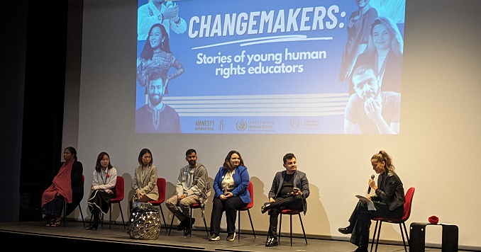 Siete jóvenes en un escenario sentados celebrando un panel de discusión