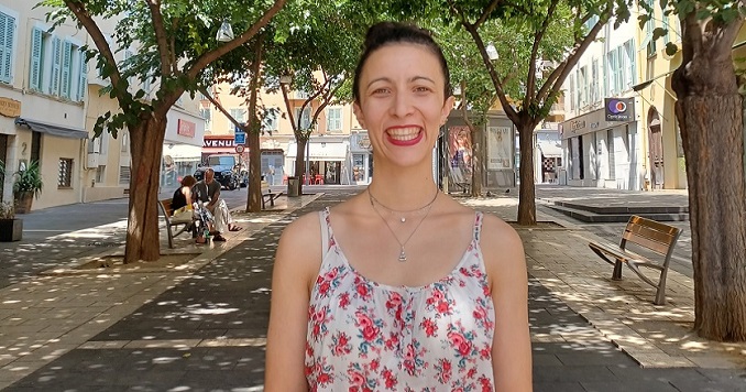 Foto retrato de una joven sonriente en una calle arbolada, en verano