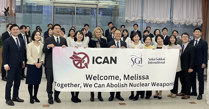 一群人在室內拿著國際廢除核武器運動的布條合影。