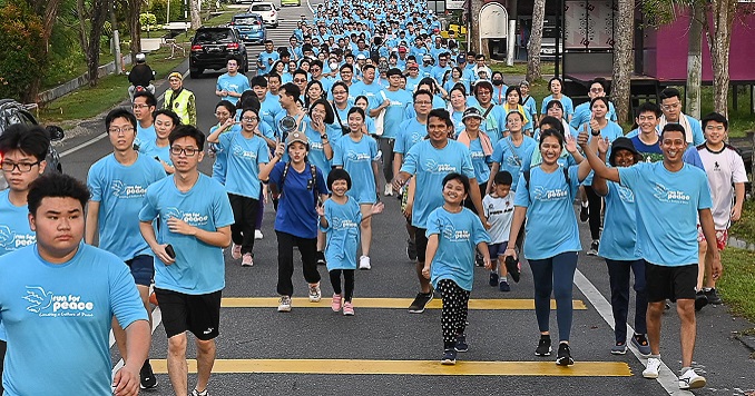 A stream of people in blue Run for Peace T-shirts fill a road Run for Peace participants in Malaka