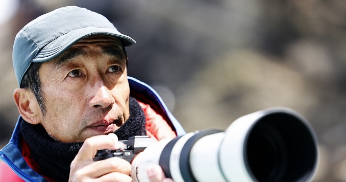 Mr. Terasawa holding a camera with a long lens