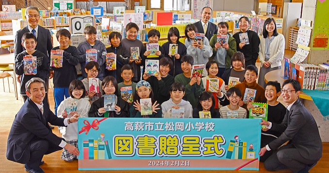 A group of children with books posing for a commemorative photo.