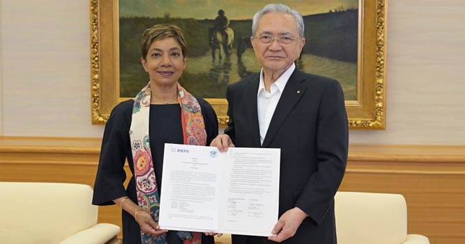 Dos personas paradas lado a lado sosteniendo un contrato firmado. 