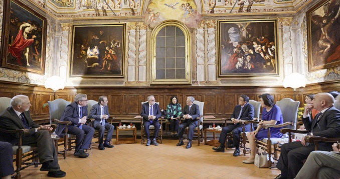 Personas sentadas en círculo, conversando en una sala con cuadros.