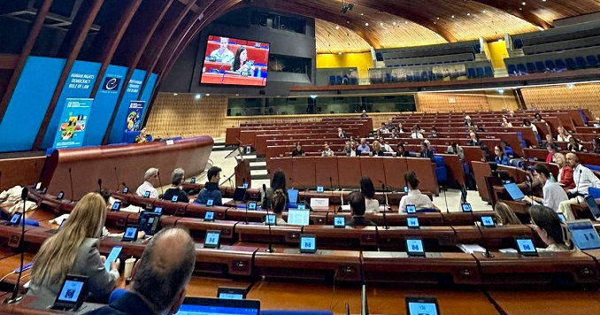 People in a large, modern conference hall listening to a speaker.