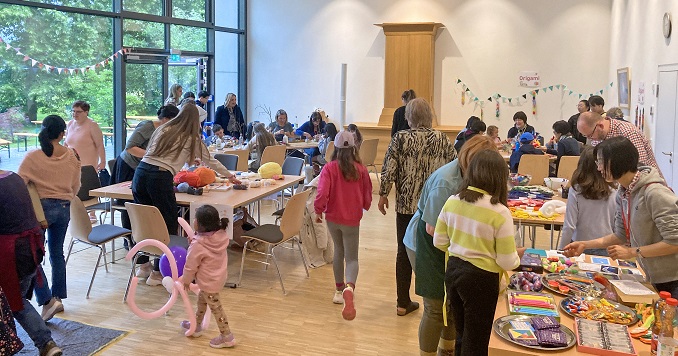 Children and adults doing arts and crafts at tables.