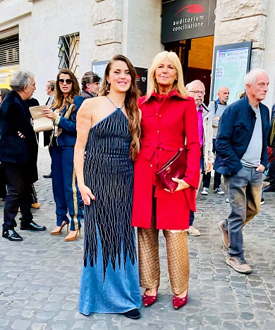 Two women standing outside an auditorium, elegantly dressed.
