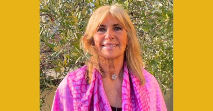 Blonde-haired woman dressed in colorful clothes, smiling at the camera.