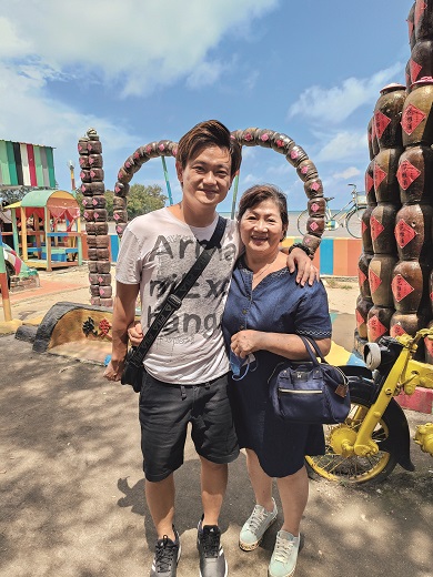 A man standing next to his mother at a theme park