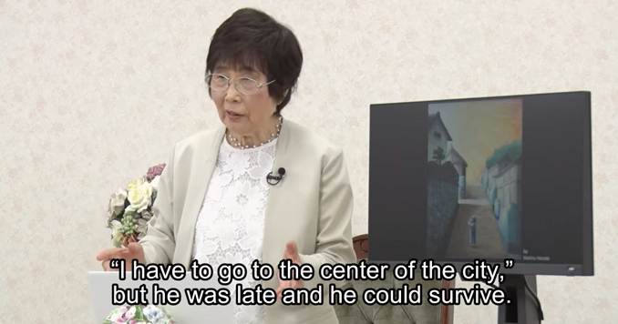 A woman, smartly dressed, standing at the front of a room, recounting her story.