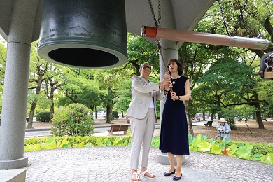 Two women ringing a bell of peace.