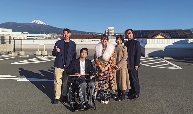 一個家庭與坐輪椅的親人合影,背景中可見富士山。
