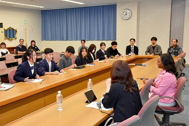 A woman and a translator sit in front of young people in a conference room.