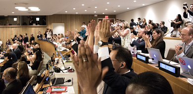 People in an auditorium sitting and applauding vigorously