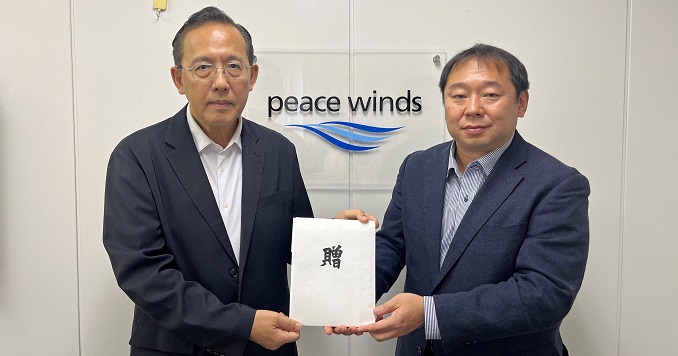 Two men in suits holding a donation envelope.