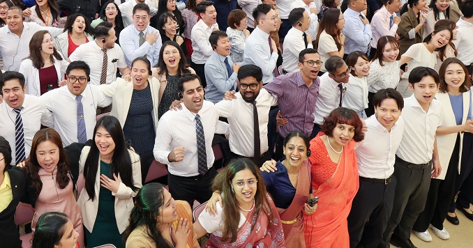 Young people singing together, standing arm in arm in a large hall.