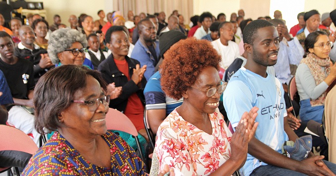 People smiling and clapping at an event.