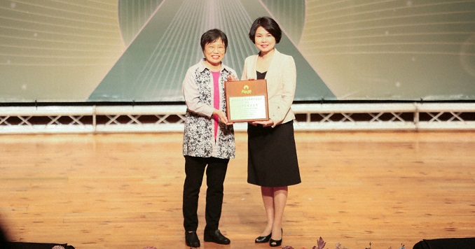 Two women in formal dress holding an award.