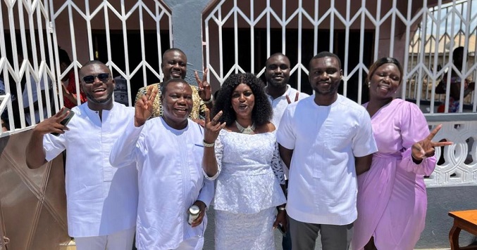 A family of seven people standing and smiling for a commemorative photograph.