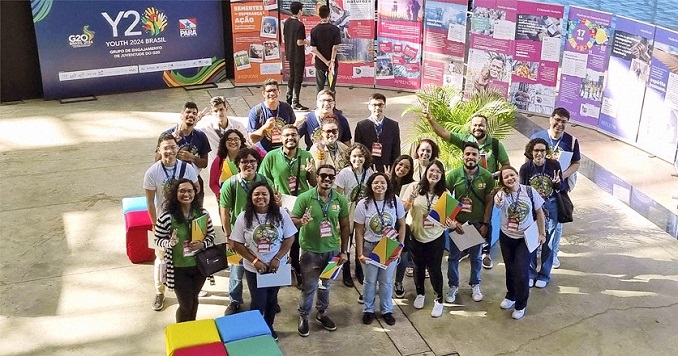 Group young people posing for a photo, in the background the exhibition “Seeds of Hope & Action: Making the SDGs a Reality”