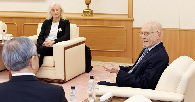 Three people engaged in discussion sitting in a meeting room.