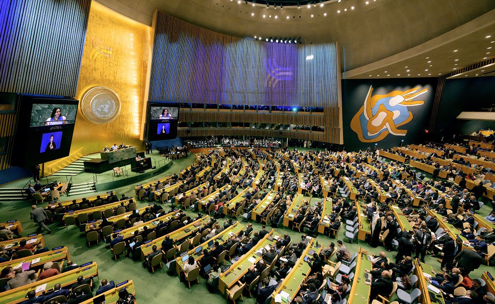 Attendees of a conference seated in a large hall.