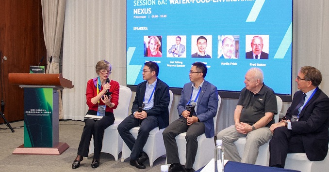 Five people taking part in a panel discussion with a large screen behind them.