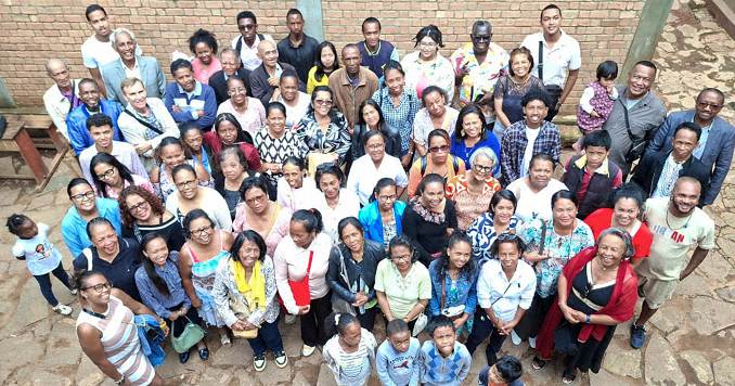 People standing in a paved area looking up at a camera and smiling.