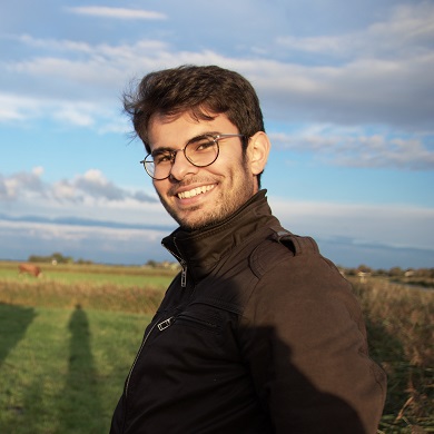 男子站在绿色草坪上与两头牛合影。